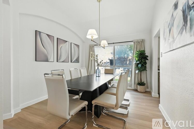 A modern dining room with a black table and white chairs.