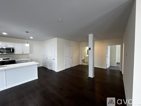 A spacious kitchen with white cabinets and a dark wood floor.