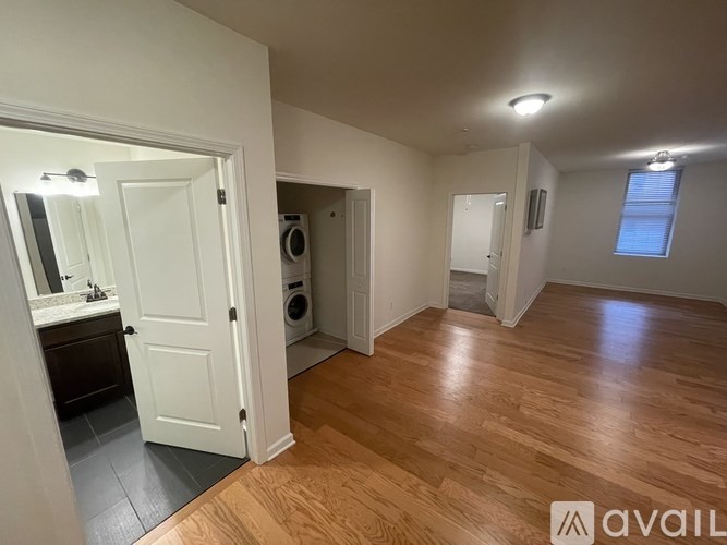 A room with wooden flooring and a white door leading to a bathroom.