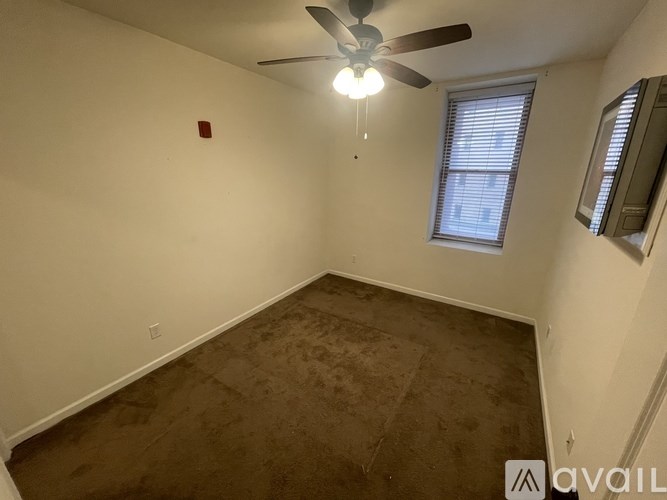 A room with a ceiling fan and a window with blinds.