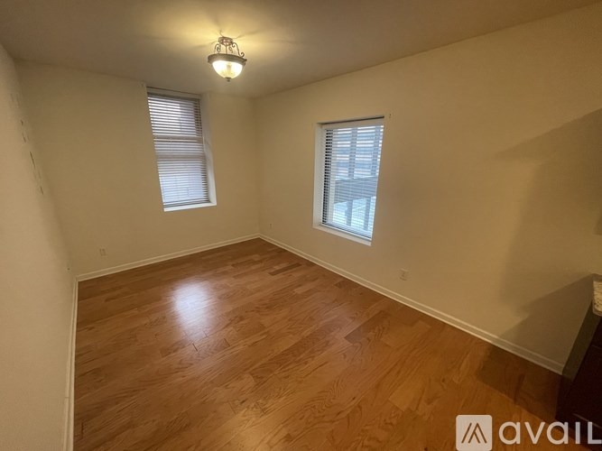 A room with wooden flooring and two windows.