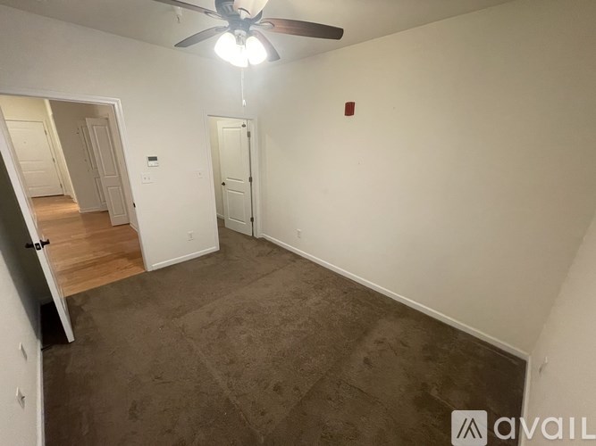 A room with a fan and carpeted floor.