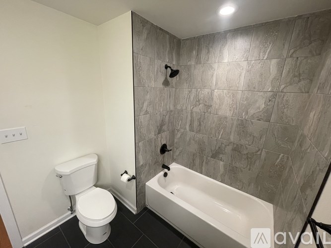 A bathroom with a toilet, a bathtub, and a shower head.