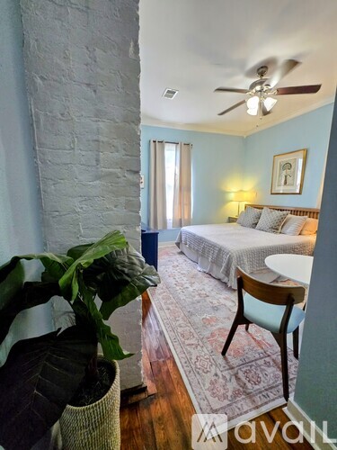A bedroom with a bed, a chair, and a potted plant.
