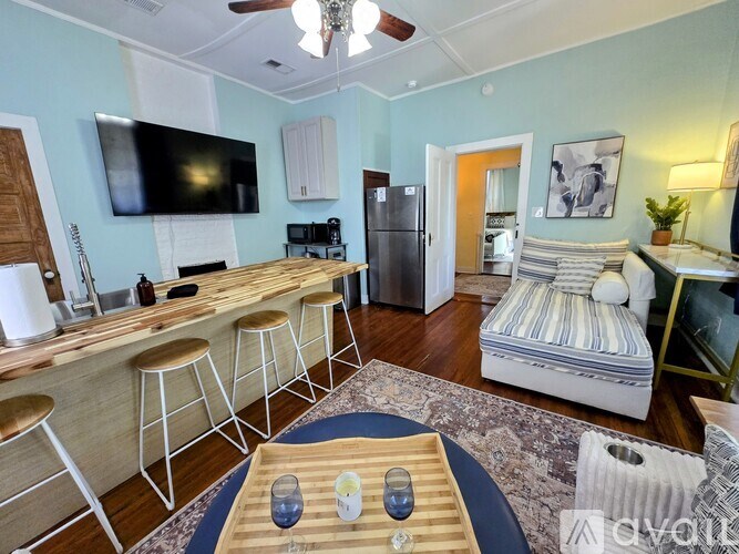 A living room with a television, bar stools, and a refrigerator.