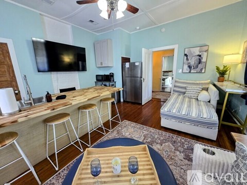 A living room with a television, bar stools, and a refrigerator.