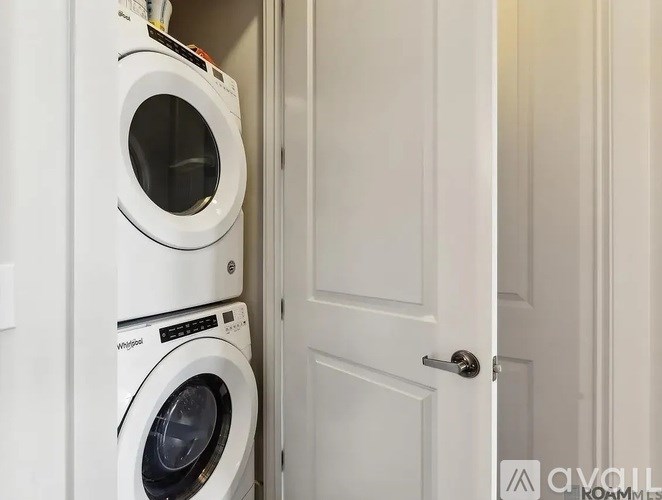 A white washing machine and dryer stacked on top of each other in a laundry room.