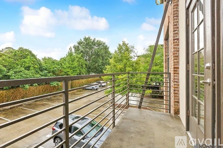 A parking lot with cars and a building with a balcony.