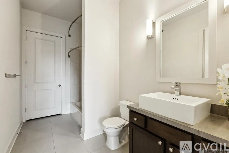 A white bathroom with a toilet, sink, and mirror.