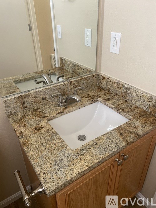 A bathroom sink with granite countertop and wooden cabinet.