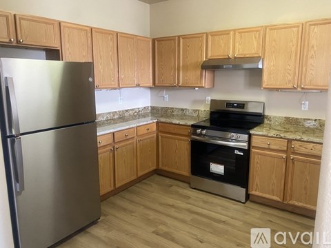 A kitchen with wooden cabinets and a stainless steel refrigerator.