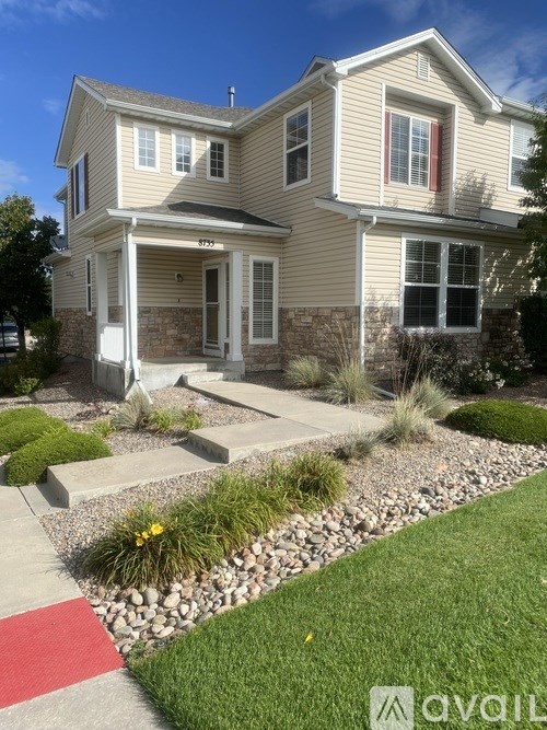 A house with a front yard and a red pathway leading to the front door.