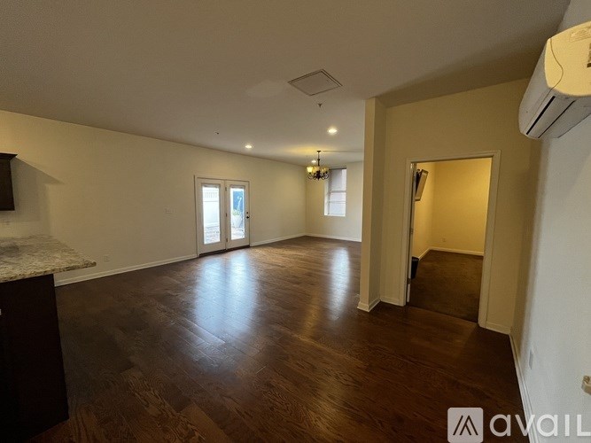 A spacious room with wooden floors and a large window.