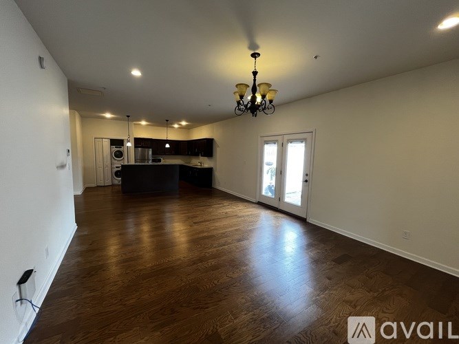 A large empty room with wooden floors and a chandelier.