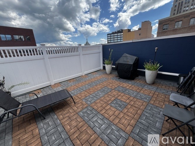 A patio with a white fence and black furniture.