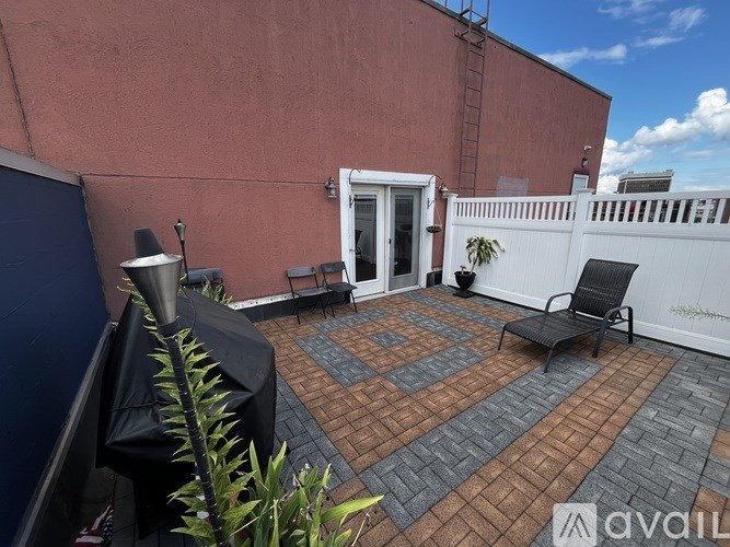 A patio with a black umbrella and a white fence.