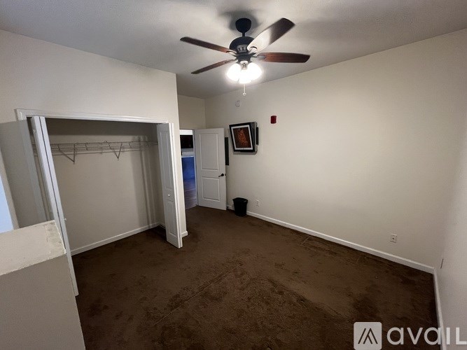A room with a ceiling fan and a brown carpet.