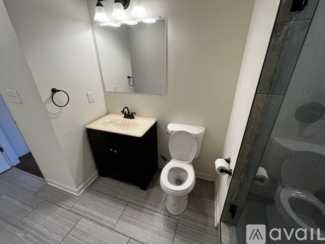 A bathroom with a toilet and a vanity with a mirror above it.