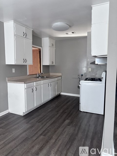 A kitchen with white cabinets and a wooden floor.