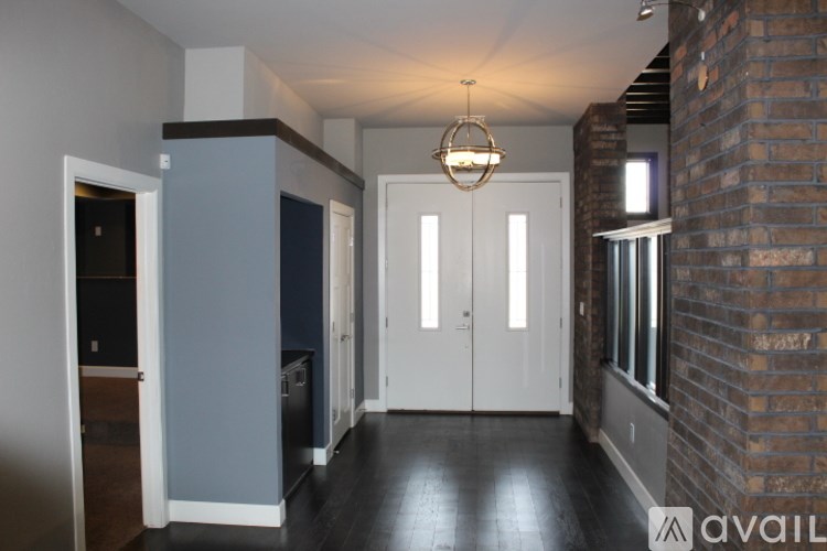 A hallway with a brick wall on the right and a chandelier hanging from the ceiling.