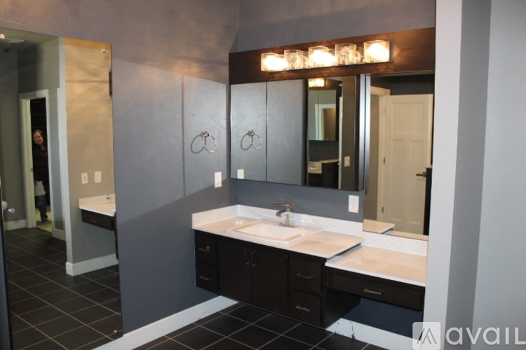 A bathroom with a sink, mirror, and black tile flooring.