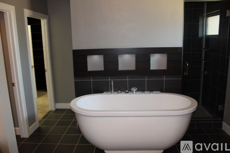 A white bathtub is in a bathroom with black tile.