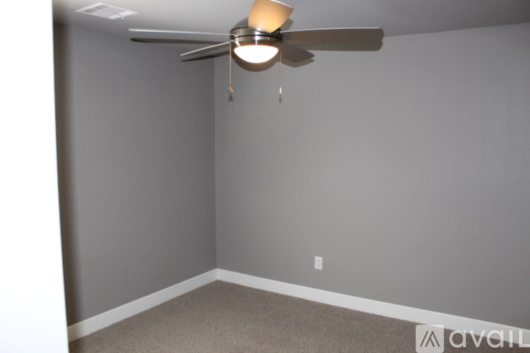 A room with a ceiling fan and carpeted floor.