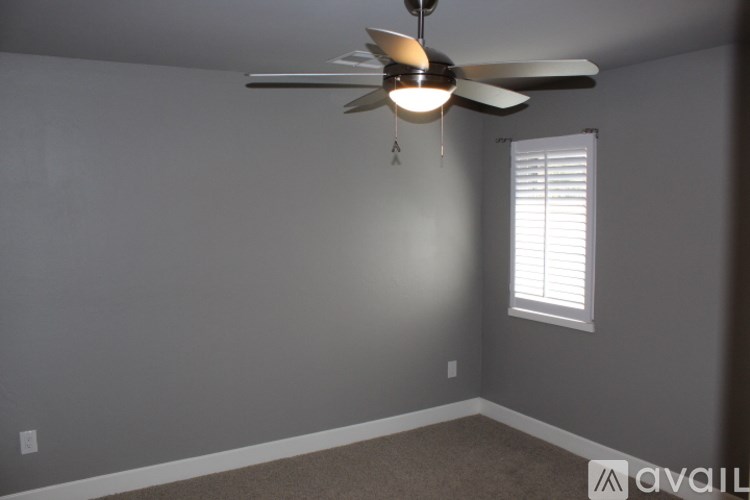 A room with a ceiling fan and a window with blinds.