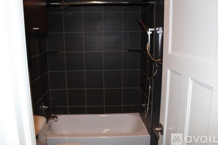 A bathroom with a white tub and black tiles.