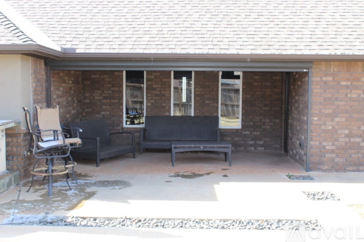 A patio with a black sofa and a chair.