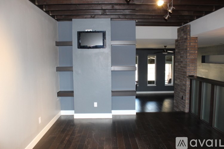 A room with a television on the wall and wooden flooring.