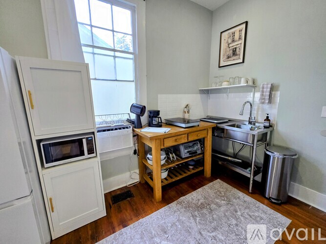 A kitchen with a refrigerator, a microwave, and a wooden door.