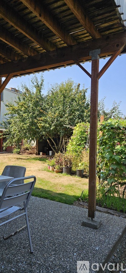A patio with a table and chairs under a wooden roof.