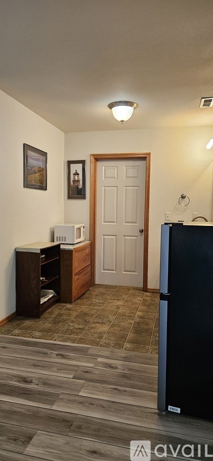 A kitchen with a black fridge and a white door.