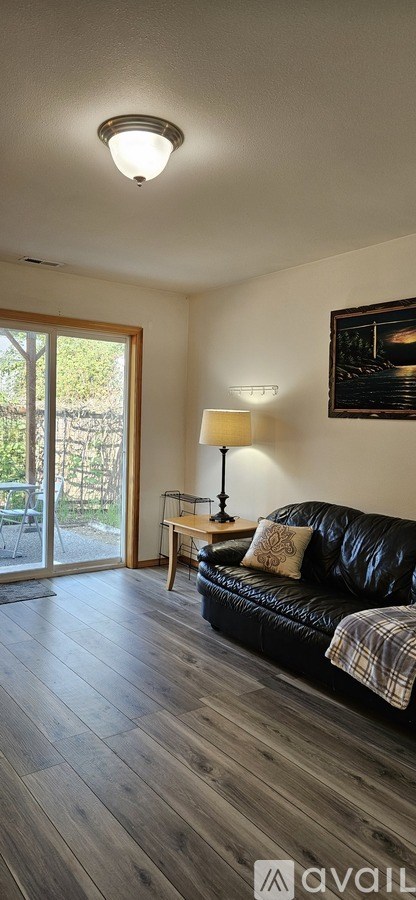 A living room with a black couch and a lamp.