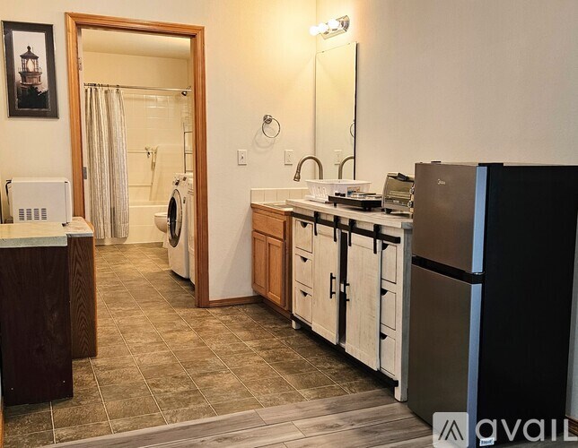 A kitchen with a black fridge and white cabinets.