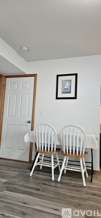 Two white chairs are placed in front of a white door.