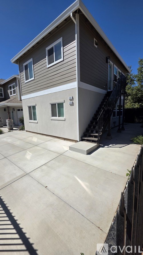 A modern house with a grey and white exterior and a black metal staircase.