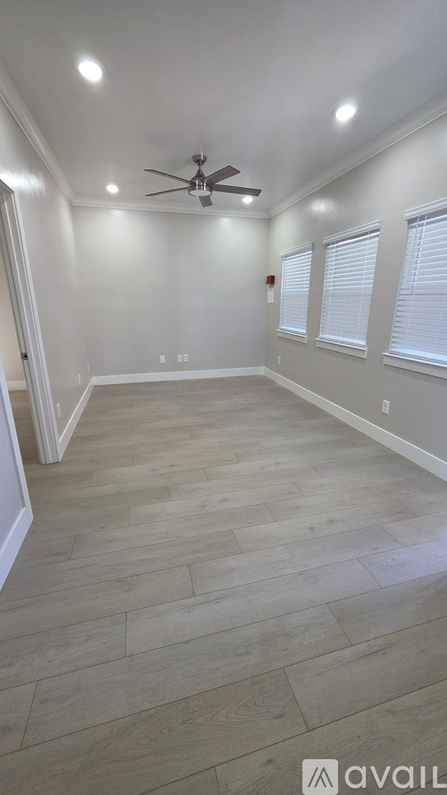 A room with a ceiling fan and wooden flooring.