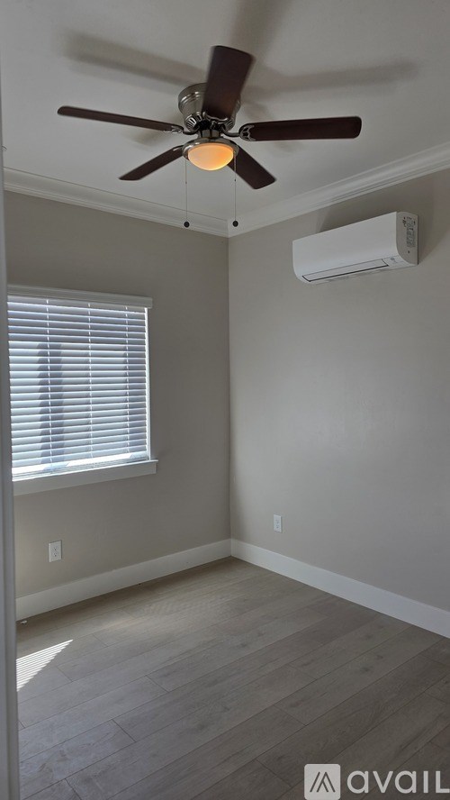 A room with a ceiling fan and a window with blinds.