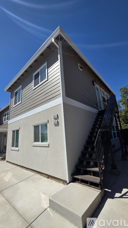 A house with a grey and white exterior and a black metal staircase.