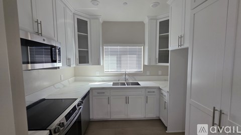 A kitchen with white cabinets and a black stove top oven.