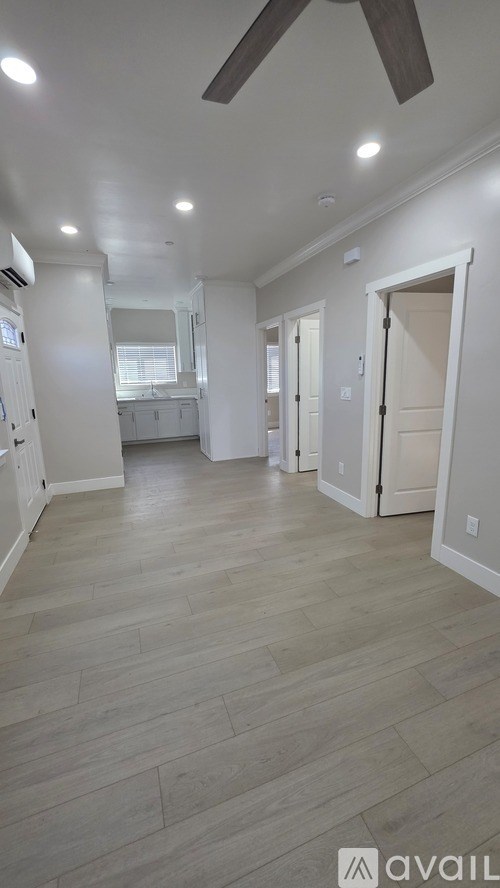A spacious room with a ceiling fan and lighting.