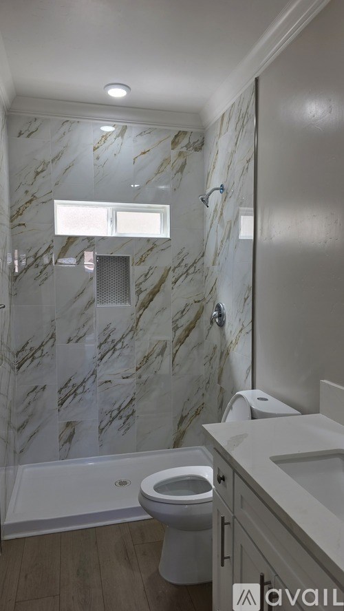A bathroom with marble tiles and a white toilet.