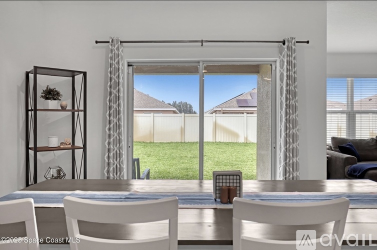 A modern dining room with a view of a backyard through a sliding glass door.
