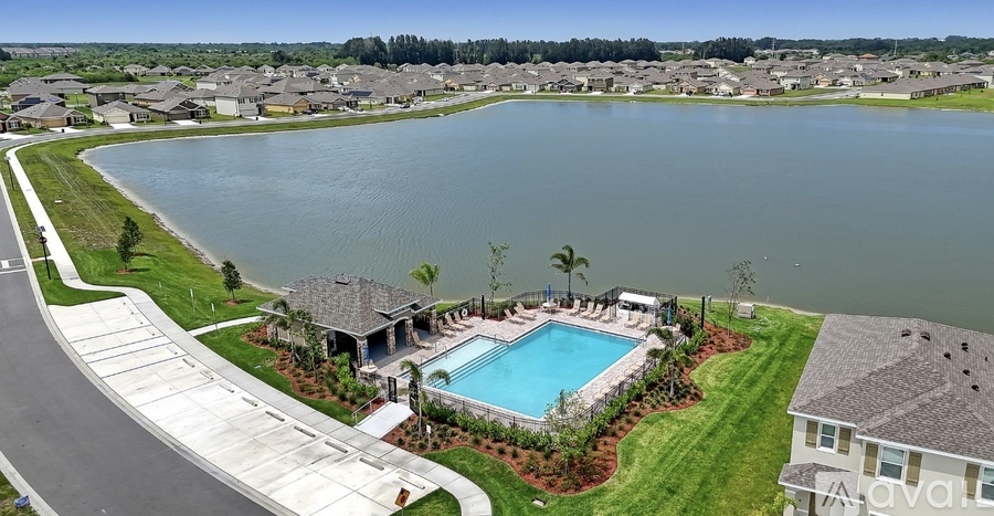 A large swimming pool is surrounded by a grassy area and a few trees.