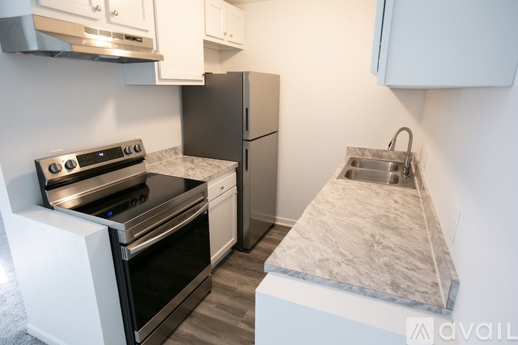 A kitchen with a stove, refrigerator, and a marble countertop.