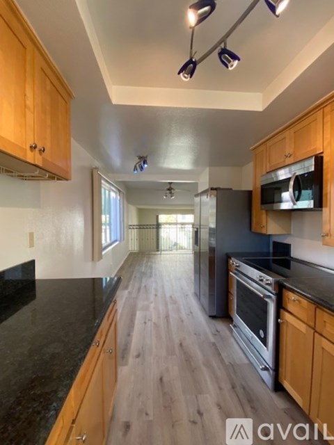 A kitchen with wooden cabinets and black countertops.