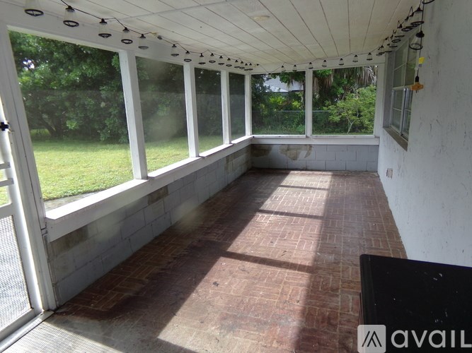 A sunroom with a brick floor and white walls.