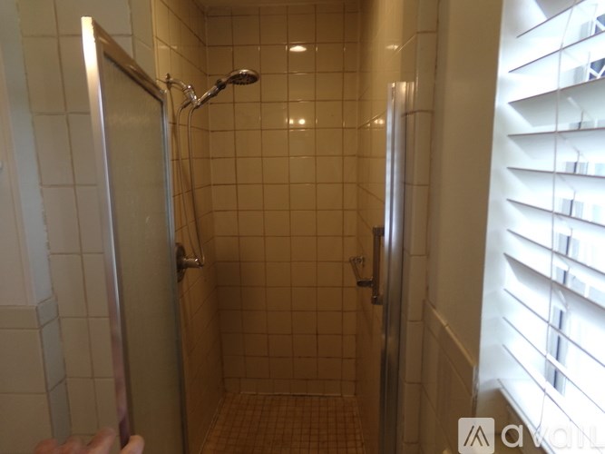 A person is opening a shower door in a tiled bathroom.